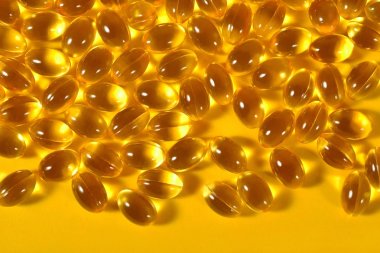 Omega-3 balık yağı kapsülleri sarı bir arka plan üzerinde şişman