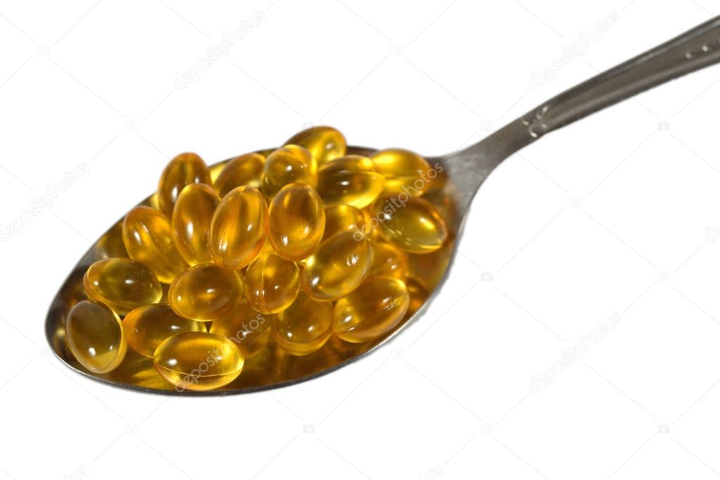 Omega-3 fish fat oil capsules in spoon on a white