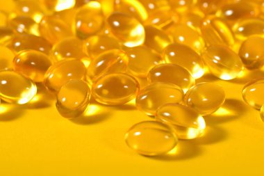 Omega-3 balık yağı kapsülleri sarı bir arka plan üzerinde yakın çekim şişman.
