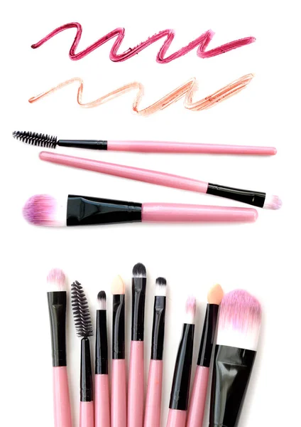 Set med rosa make-up borstar med läppstift spår isolerade på vit bakgrund. — Stockfoto