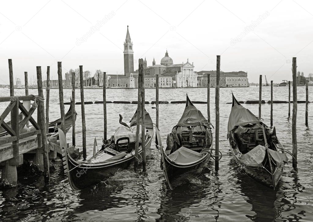 Black and white of Gondolas moored by Saint Mark square with San Giorgio di Maggiore church in the background - Venice, Venezia, Italy, Europe