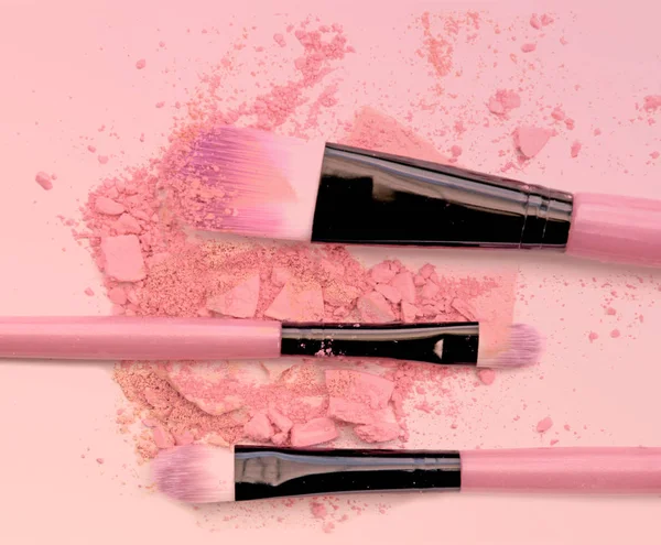 Brush make up set crushed make up power on pink background.