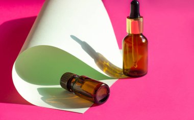 Açık pembe arka planda koyu gölgeli cam kozmetik şişeler. Güzellik blogcusu, prosedür salonu konsepti. Minimalizm. Pembe arka planda kozmetik düşürücü.