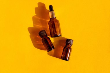 Kumlu parlak bir arka planda sert gölgeli cam kozmetik şişeler. Güzellik blogcusu, prosedür salonu konsepti. Minimalizm. Pembe arka planda kozmetik düşürücü.