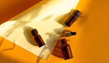 Kumlu parlak bir arka planda sert gölgeli cam kozmetik şişeler. Güzellik blogcusu, prosedür salonu konsepti. Minimalizm. Pembe arka planda kozmetik düşürücü.