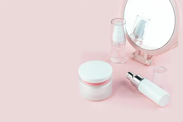 Cosmetic bottles with serum, gel, face cream on a pink background with a mirror. Skin cosmetics, minimalism — Stock Photo, Image