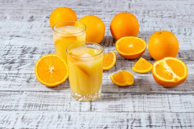 Bir bardak portakal suyu ve ahşap bir masada portakal tabağı. Taze sıkılmış portakal suyu.