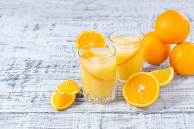 Bir bardak portakal suyu, ahşap bir masada buz ve portakallı bir tabak.