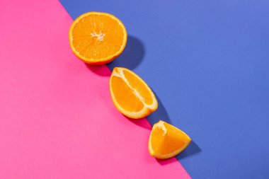 Parlak pembe ve mavi arka planda dilimler halinde dilimlenmiş turuncu sert gölgeler..