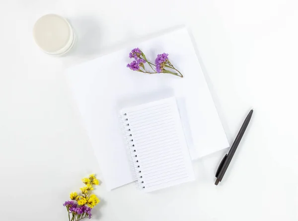 Female workspace with blank open notebook for writing, pen and flowers on a white table. Top view, flat lay, copy space, minimalism. Space for adding text. — Stockfoto