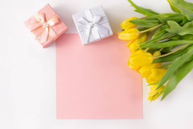 Beyaz arka planda bir buket sarı lale ve hediye kutuları. Not eklemek için yer var.