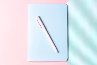 Düz yerde kadın işyeri vardı. Pembe arka plandaki defter ve kalem. Blogların ve sosyal ağların tasarımı.