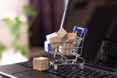 İnternetten alışveriş ve ev teslimatı. Alışveriş sepeti ve kutular dizüstü bilgisayarda.
