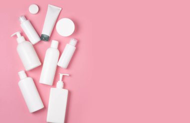 Pembe arka planda beyaz plastik kutular. Cilt bakımı için kozmetik. Yıkama, dezenfekte etme ve yıkama araçları.