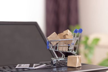 İnternetten alışveriş ve ev teslimatı. Alışveriş sepeti ve kutular dizüstü bilgisayarda.