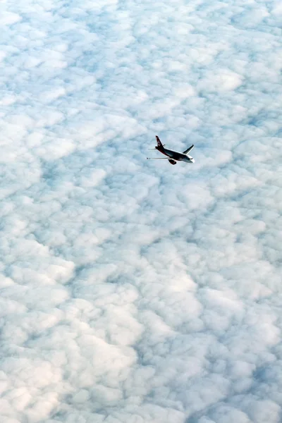 Airplane flying above a dense white cloud layer — Stock Photo, Image