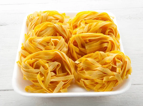 Uncooked rolls of Italian tagliatelle noodles — Stock Photo, Image