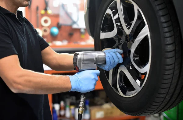 Mecânico mudando um pneu de carro em uma oficina — Fotografia de Stock