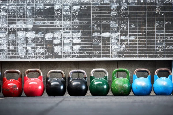 Row of colorful pairs of kettlebell weights — Stock Photo, Image