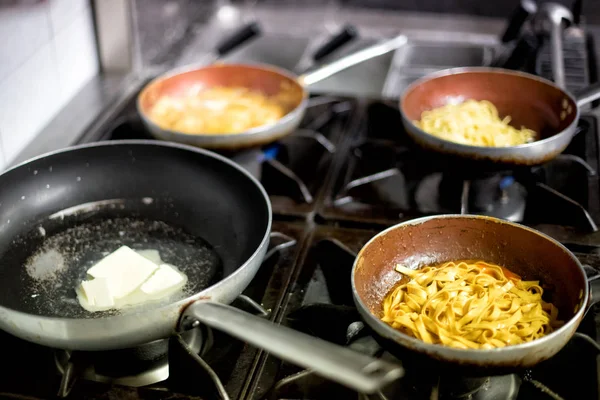Four frying pans on burners in restaurant — Stock Photo, Image
