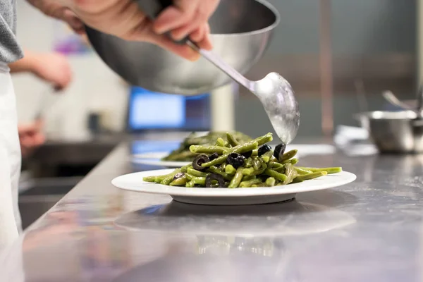 Chef serving fresh green bean salad from a bowl — Stock Photo, Image