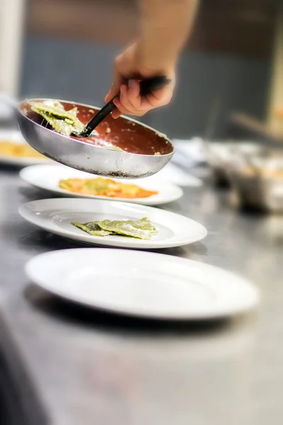 Chef serving ravioli pasta in a restaurant kitchen — Stock Photo, Image
