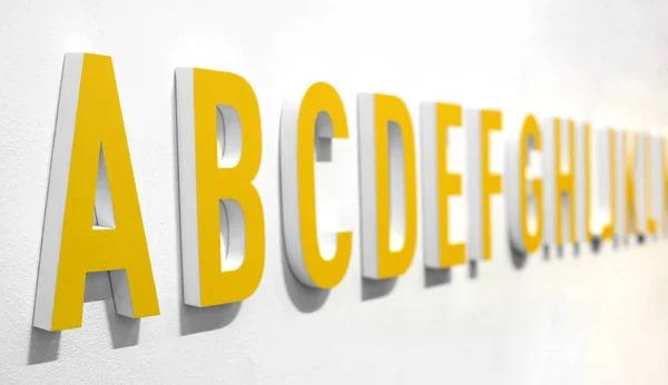 Lettrage alphabet jaune 3d sur un mur — Photo