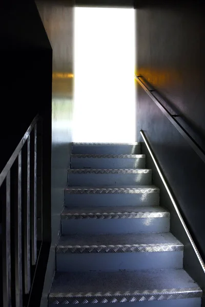 Escaleras metálicas de una escalera hacia una puerta abierta — Foto de Stock