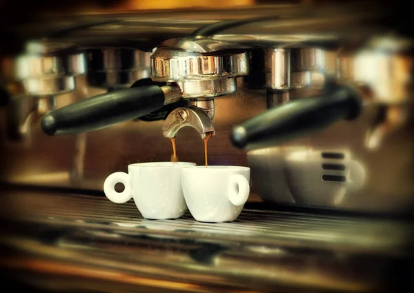 Cafeteira derrama café quente em duas xícaras brancas — Fotografia de Stock