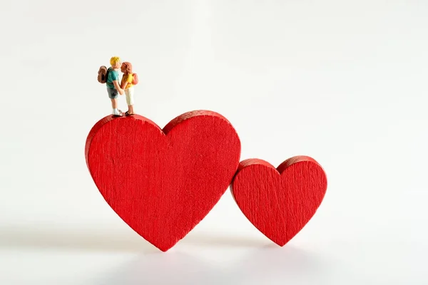 Miniature figures of two young people on a heart — Stock Photo, Image