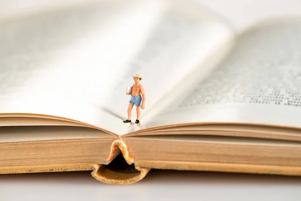 Figura in miniatura di un uomo che cammina su un libro aperto — Foto Stock