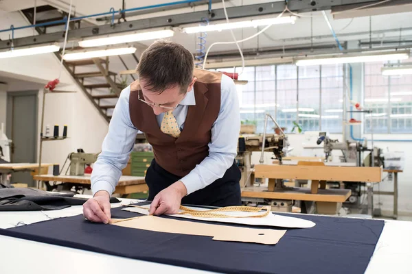 Tailor laying out paper patterns on blue fabric — Stock Photo, Image