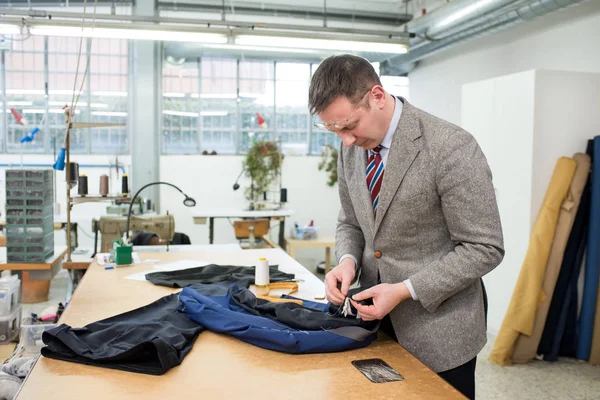 Tailor hand sewing the lining in a blue jacket — Stock Photo, Image