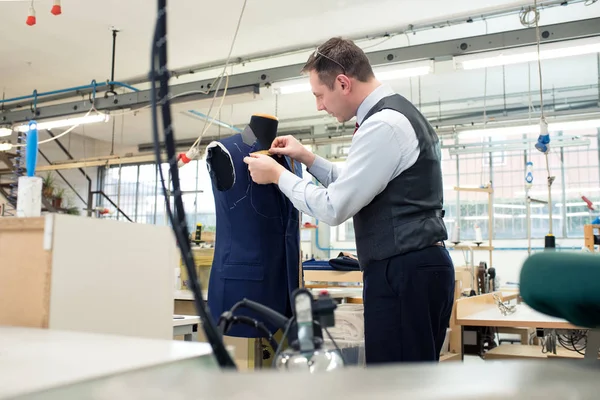 Tailor standing working on a blue jacket — Stock Photo, Image