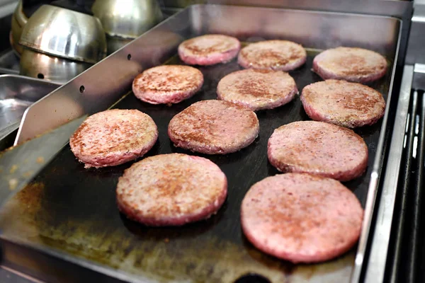 Rangées de galettes de hamburger cuisson sur une plaque chauffante — Photo