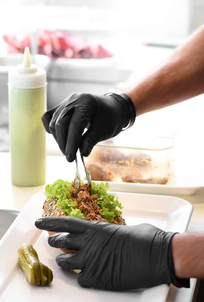 Kocken förbereder en drog fläsk smörgås — Stockfoto