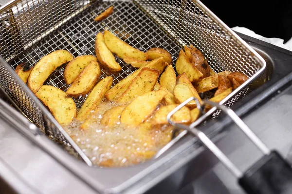 Spicy potato chips or wedges in a deep fryer — Stock Photo, Image