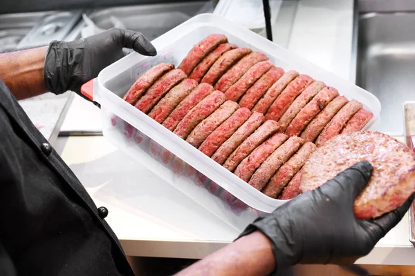 Chef holding a tray of pre-cooked beef patties — Stock Photo, Image