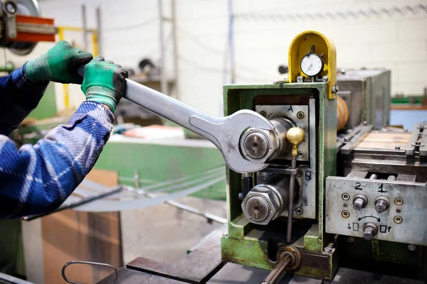 Worker adjusting machinery with large wrench — Stock Photo, Image