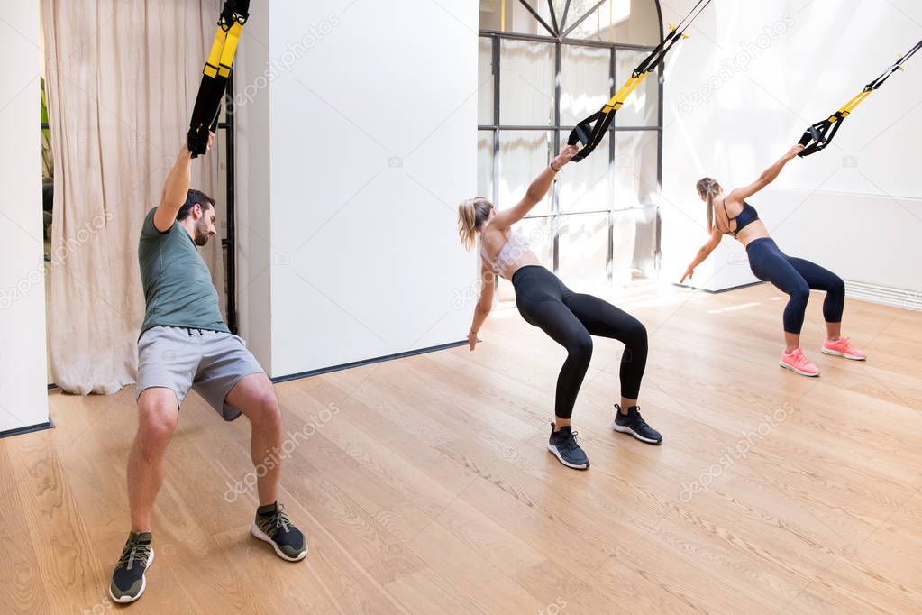Three people working out doing Trx power pulls