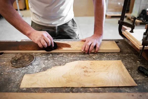 Carpenter applying stain to a briar root panel — Stock Photo, Image