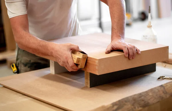 Hände eines Tischlers schleifen die Kante eines Blocks — Stockfoto