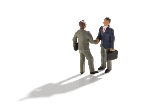 Miniature businessmen shaking hands on white — Stock Photo, Image