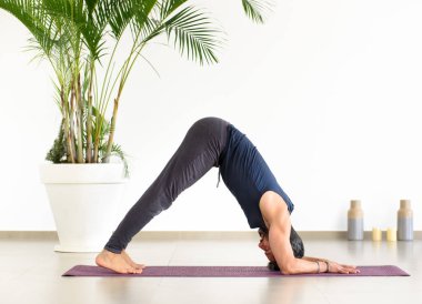 Spor salonunda egzersiz yaparken yoga yunusu pozu veren zinde bir adam sağlık ve zindelik konseptinde düşük açılı bir yan görünüm takınıyor.