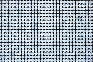 Koyu arkaplan dokusu efekti üzerine tepeden görülen küçük parlak metalik disklerin satırları tam kare olarak görüntülenir