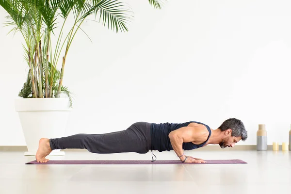 适合男人做瑜伽沙土兰加俯卧撑期间 他的锻炼在一个高调健身房与盆栽手掌在一个低角度的健康和健康的概念侧面看 — 图库照片