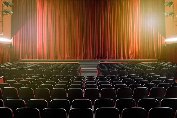 舞台芸術のコンセプトで幕を閉じた赤いカーテンで舞台に向かって後ろから空の席が見える大きな照明劇場 — ストック写真