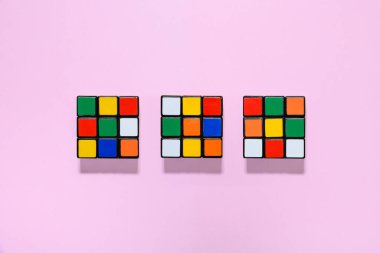 Üç renkli Rubik küpü pembe bir arkaplan üzerine kurulmuş, her yeri gölgeli ve kopyalayıcı alan.