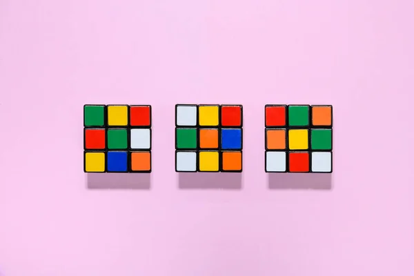 Drei Farbenfrohe Rubiks Würfel Einer Aufgeräumten Reihe Auf Rosa Hintergrund — Stockfoto