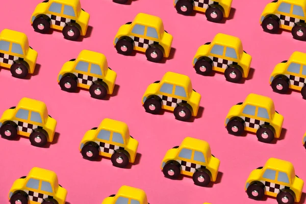 カラフルなピンクの背景に小さな黄色のおもちゃのタクシーやタクシーの行は フルフレームで高い角度を見た — ストック写真